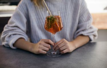 Woman holding an aperitif glass with rosemary sprig at Hotel Bühelwirt, Ahrntal