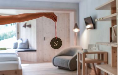 Hand holding a round sign reading "Sì" in a design room at Hotel Bühelwirt, Ahrntal