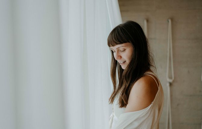 Junge Frau in entspannter Stimmung neben weißem Vorhang – Yoga Retreat im Biohotel Bühelwirt, St. Jakob im Ahrntal