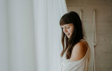 Junge Frau in entspannter Stimmung neben weißem Vorhang – Yoga Retreat im Biohotel Bühelwirt, St. Jakob im Ahrntal